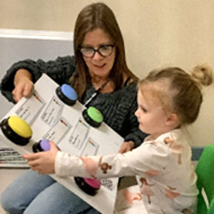 Teacher showing child a board with coloured buttons and text